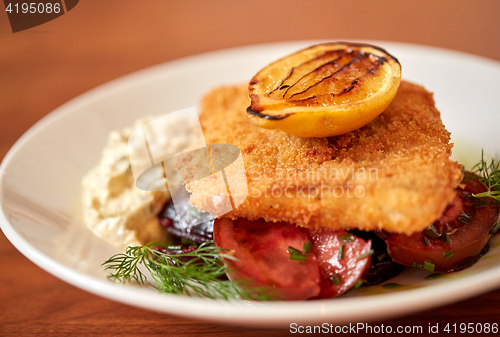 Image of close up of fish salad with roasted lemon on plate