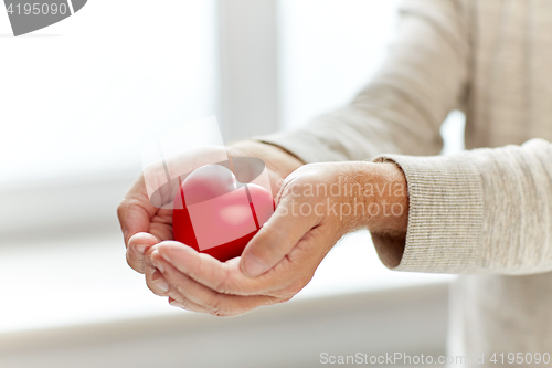 Image of close up of senior man with red heart in hands