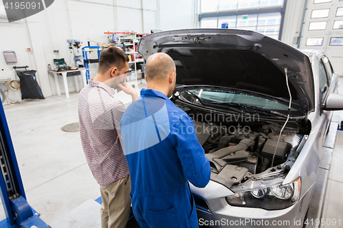 Image of auto mechanic and man or car owner at workshop