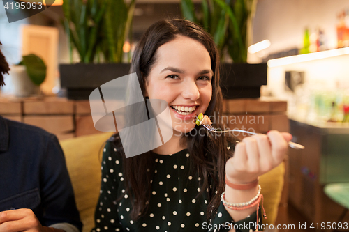 Image of happy young woman eating at restaurant