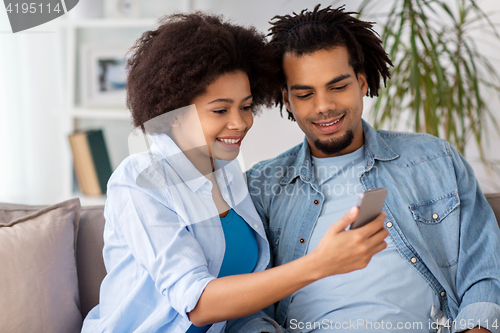 Image of happy couple with smartphones at home