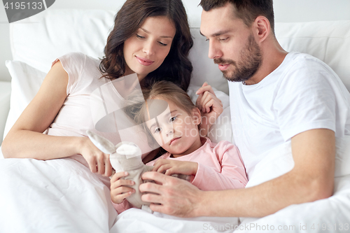 Image of happy child with toy and parents in bed at home
