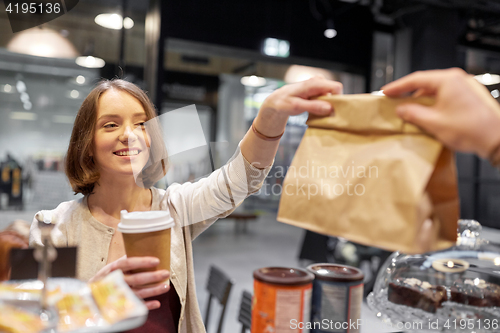 Image of woman taking paper bag from seller at cafe