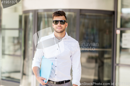 Image of young man with business file on city street