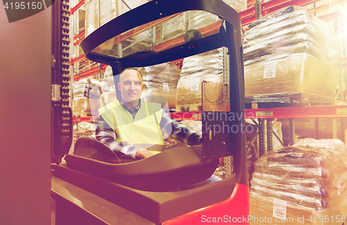 Image of smiling man operating forklift loader at warehouse