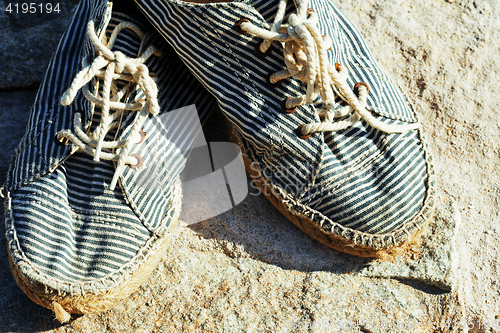 Image of picture of vintage old shabby sneakers at seacost, real forgotte