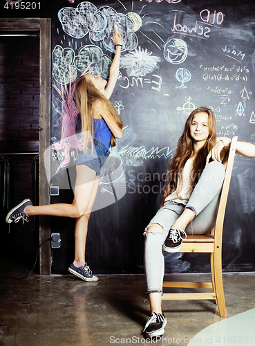 Image of back to school after summer vacations, two teen girls in classroom with blackboard painted together
