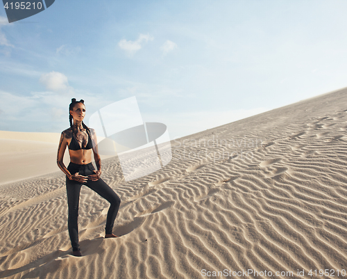 Image of young pretty woman in white sand dunes like a goddes of darkness
