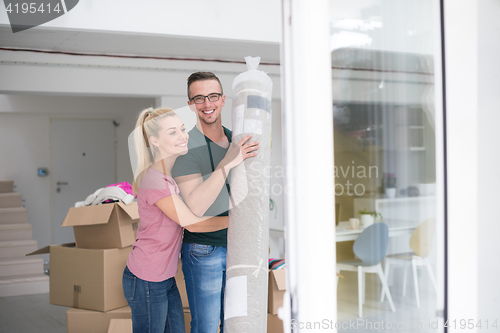 Image of couple carrying a carpet moving in to new home