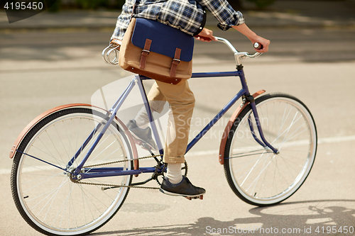 Image of young hipster man with bag riding fixed gear bike