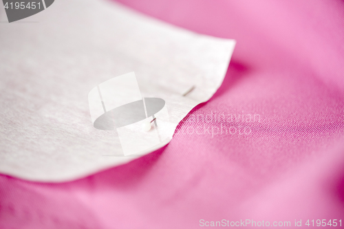 Image of paper pattern attached with sewing pin to cloth