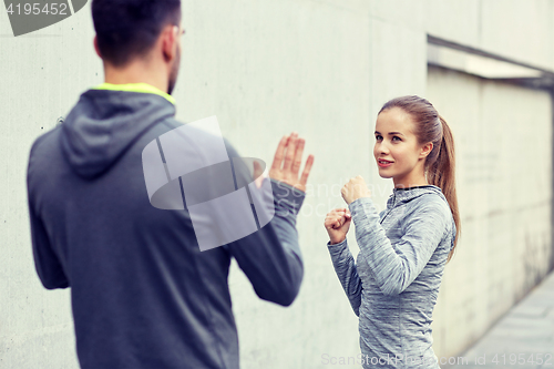 Image of happy woman with coach working out strike outdoors