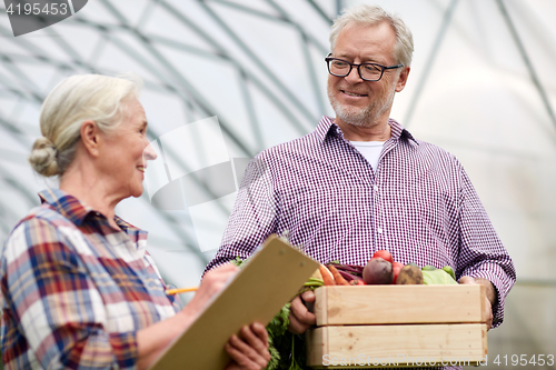 Image of senior couple with box of vegetables on farm