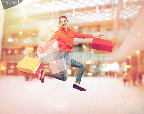 Image of smiling young woman with shopping bags jumping