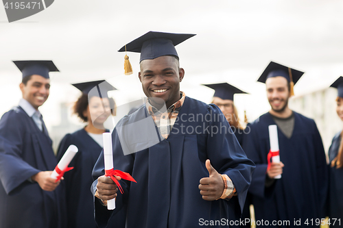 Image of happy students with diplomas showing thumbs up