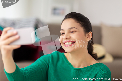 Image of happy young woman taking selfie with smartphone