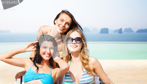 Image of happy young women in bikinis on summer beach