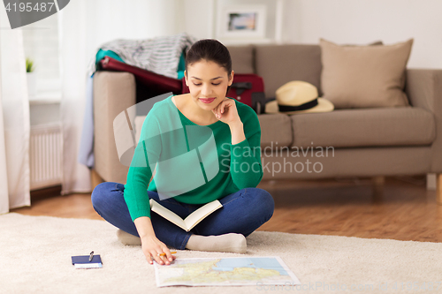 Image of woman with notebook and travel map at home