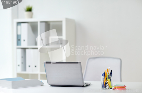 Image of laptop with pen and stickers on office table