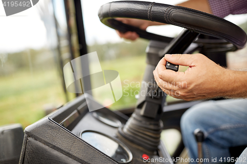 Image of senior man driving tractor at farm