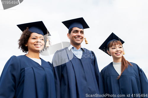 Image of happy students or bachelors in mortarboards