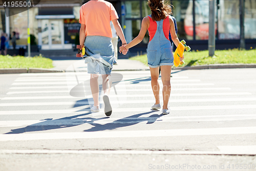 Image of teenage couple with skateboards at city crosswalk