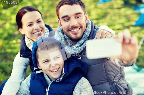 Image of family with smartphone taking selfie at campsite