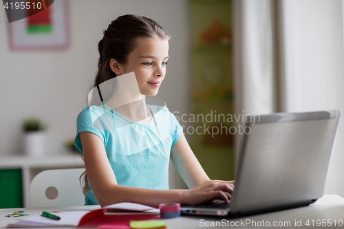 Image of happy girl typing on laptop at home