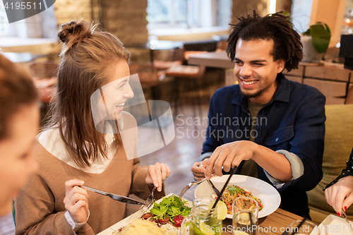 Image of happy friends eating and drinking at restaurant