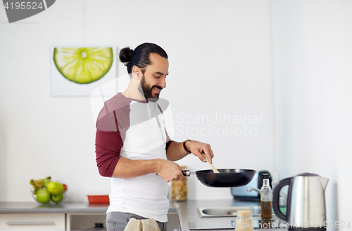 Image of man with frying pan cooking food at home kitchen