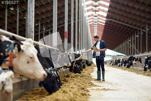 Image of farmer with clipboard and cows in cowshed on farm