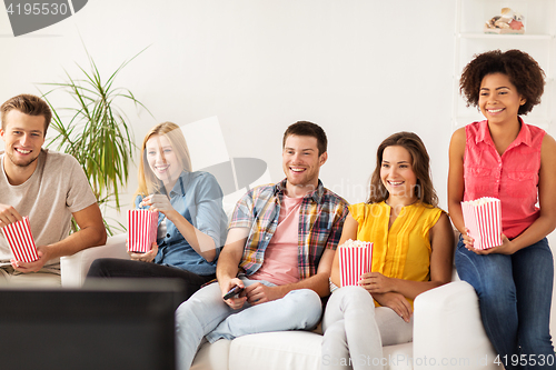 Image of happy friends with popcorn watching tv at home