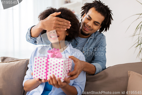 Image of happy couple with gift box at home