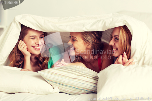 Image of happy young women in bed at home pajama party