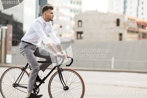 Image of man with headphones riding bicycle on city street