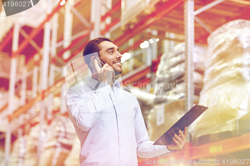 Image of man with clipboard and smartphone at warehouse