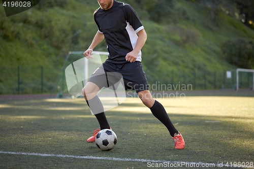 Image of soccer player playing with ball on football field