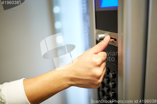 Image of hand inserting euro coin to vending machine