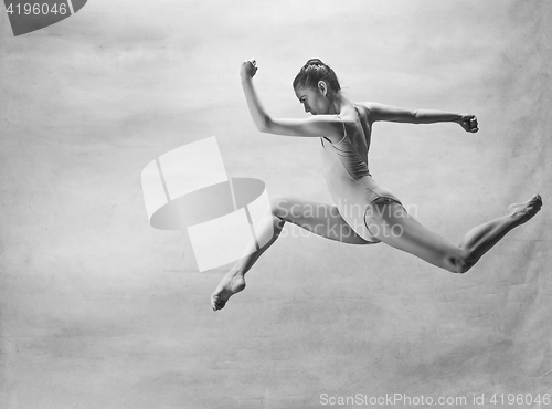 Image of Young beautiful modern style dancer jumping on a studio background