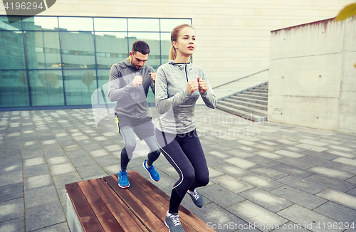 Image of couple making step exercise on city street bench