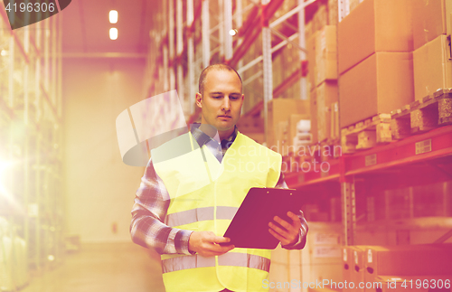 Image of man with clipboard in safety vest at warehouse