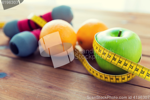 Image of close up of dumbbell, fruits and measuring tape