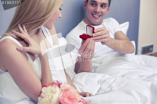 Image of close up of man giving woman engagement ring