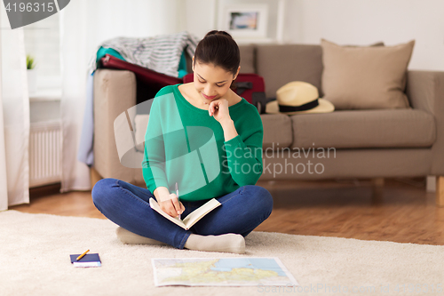 Image of woman with notebook and travel map at home