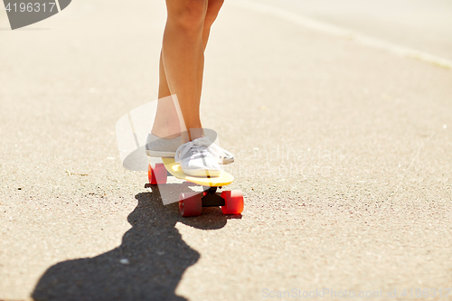 Image of legs of young woman riding skateboard on road