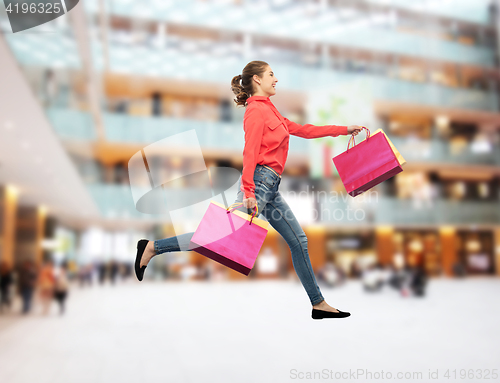 Image of smiling young woman with shopping bags running