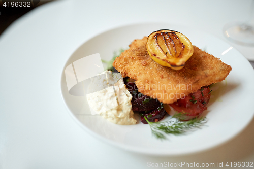 Image of close up of fish salad with roasted lemon on plate