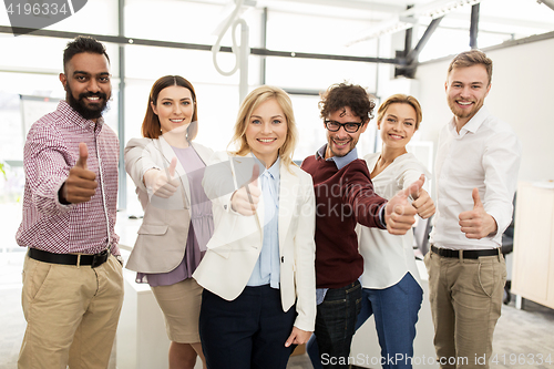 Image of happy business team showing thumbs up at office