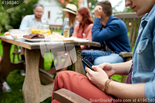 Image of man with smartphone and friends at summer party