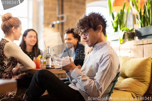 Image of man with smartphone and friends at restaurant